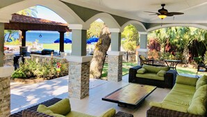 An outdoor patio area with seating, a ceiling fan, and a view of the ocean.