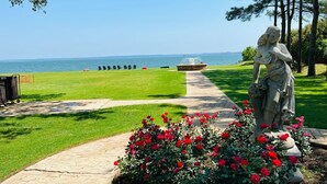 A statue in a garden with a pathway leading to a body of water.