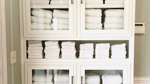 A white cabinet with multiple shelves and drawers, containing neatly folded white towels.