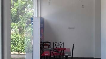 A room with a dining table and chairs, a ceiling fan, and a view through a glass door to an outdoor area.
