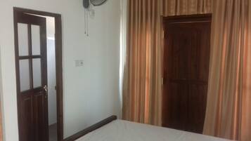 A room with a bed, a wooden door, and a curtain.