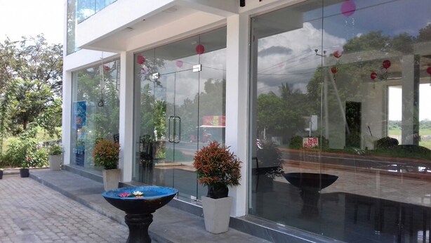A modern building with large glass doors, potted plants, and a blue water feature. - Padmasiri Holiday Resort (Anuradhapura)