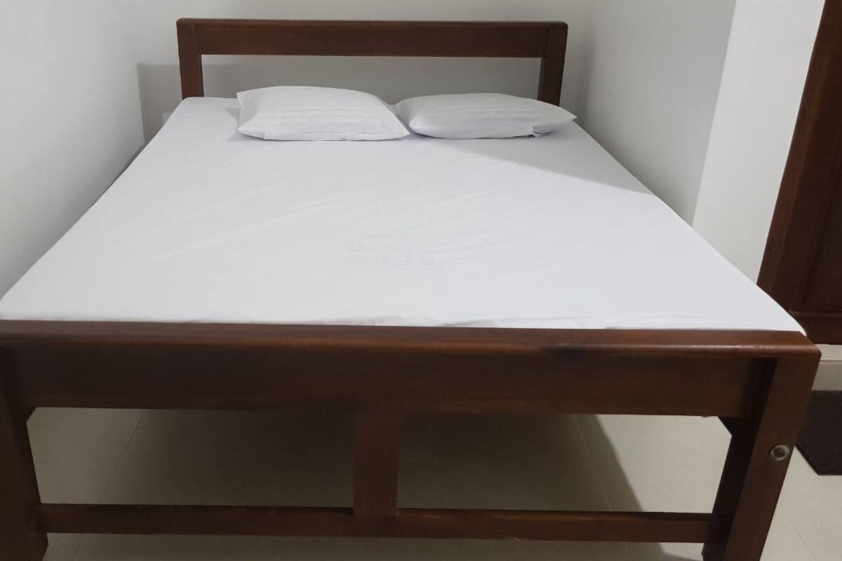 Ein Einzelbett mit Holzbettgestell und weißer Bettwäsche.