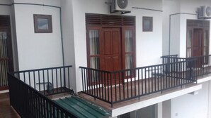 A balcony with a black railing, a wooden door, and an air conditioning unit mounted on the wall. - Padmasiri Holiday Resort (Anuradhapura)