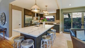 A modern kitchen with a large island, stainless steel appliances, pendant lighting, and a view of the outdoors. - Sonoma Vineyard Estate - 3bd/2bth (Sonoma)