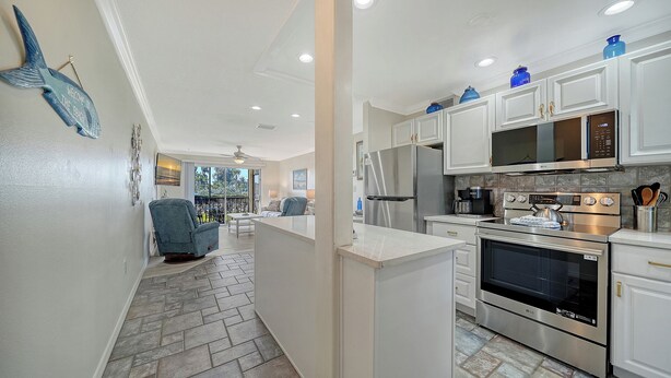 A modern kitchen with stainless steel appliances, white cabinetry, and a view to the outside. - Condo # 110 Ground floor unit with quick access to Siesta Beach Amenities (Sarasota)