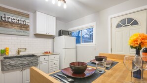 A modern kitchen with white cabinets, a stone countertop, a microwave, and a refrigerator. - The Immaculate Guest Cottage In Downtown Coeur  D'Alene (Coeur d'Alene)