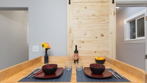 A dining table with two red bowls, two wine glasses, and a bottle of wine. - The Immaculate Guest Cottage In Downtown Coeur  D'Alene (Coeur d'Alene)
