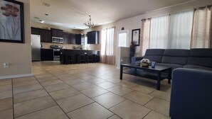 Una sala de estar con sofá, una mesa de centro y una cocina al fondo.