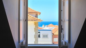 A view through an open window with a clear sky and buildings with tiled roofs.