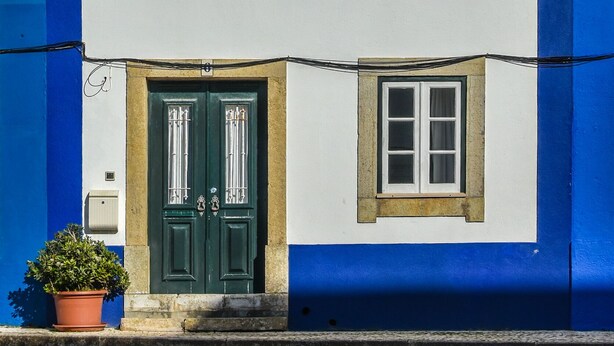 A building with a white facade, blue vertical stripes, and a green door.