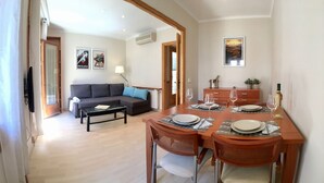 Uma sala de estar moderna com um sofá, uma mesa de centro e um espaço de jantar com uma mesa posta para dois.