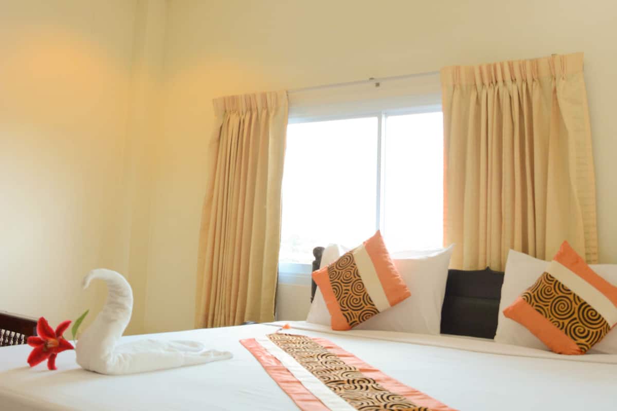 A hotel room with a bed, curtains, a window, and a ceiling light.