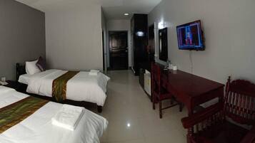 A hotel room with two beds, a desk, and a television.