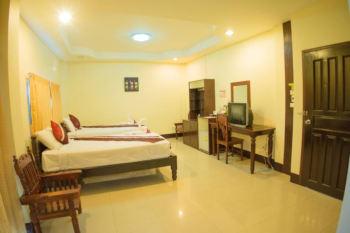 A hotel room with two beds, a desk with a television, and a wardrobe.