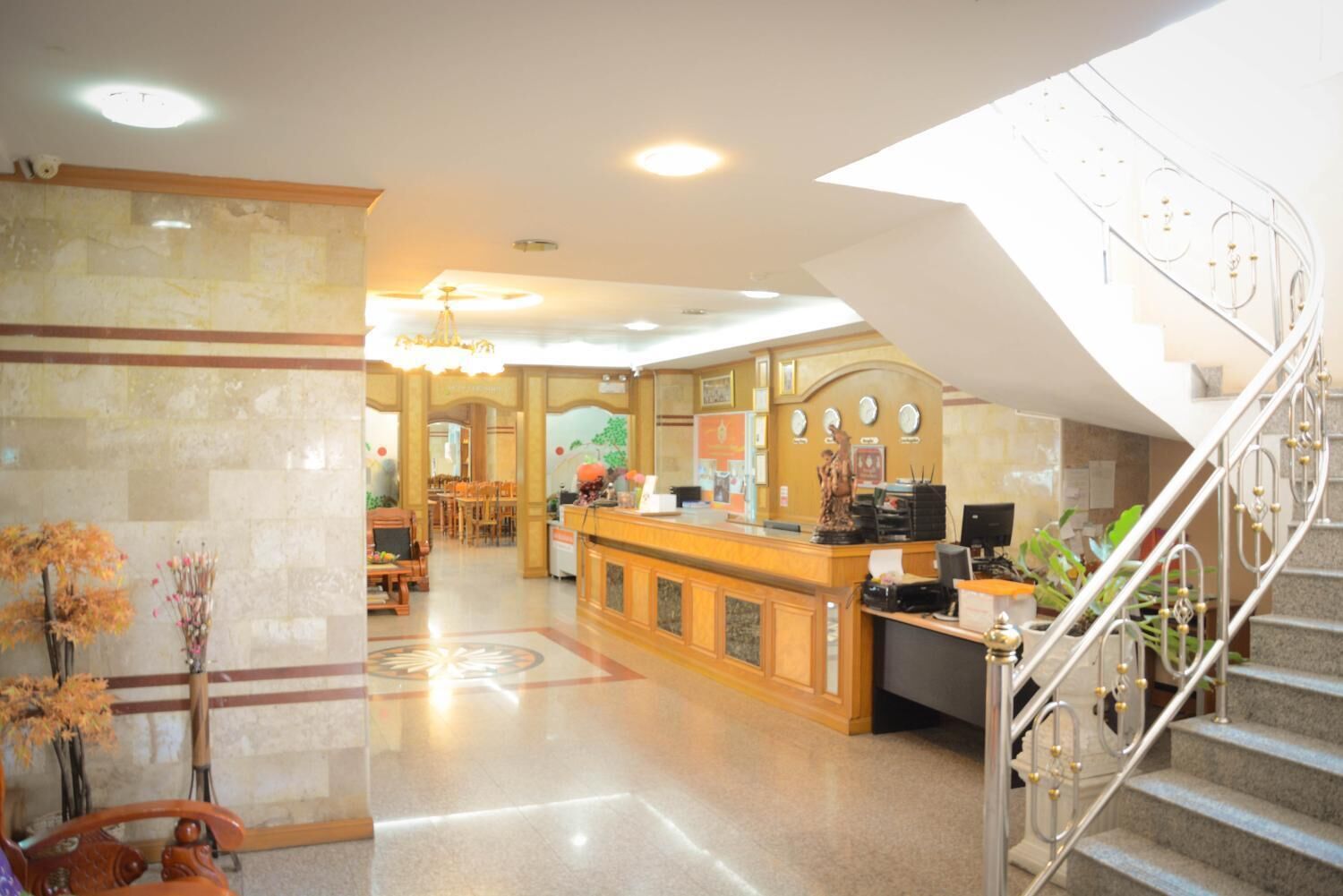 Un hall d’hôtel comprenant un comptoir d’accueil, un escalier et un espace repas.
