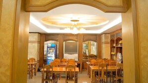 A coffee shop interior with wooden furniture, a chandelier, and a sign above the entrance. - Submukdaphoomplace Hotel (Mukdahan)