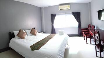 A hotel room with a large bed, a desk, and a chair.