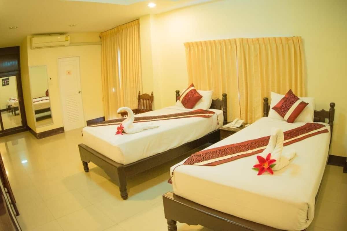 A hotel room with two beds, a mirror, a desk, and a chair.