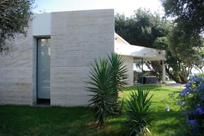 A modern building with a minimalist design, featuring a flat roof and a large glass door. - Dream location- Modern villa with pool by the sea, just a stone's throw from Rome. (Anzio)