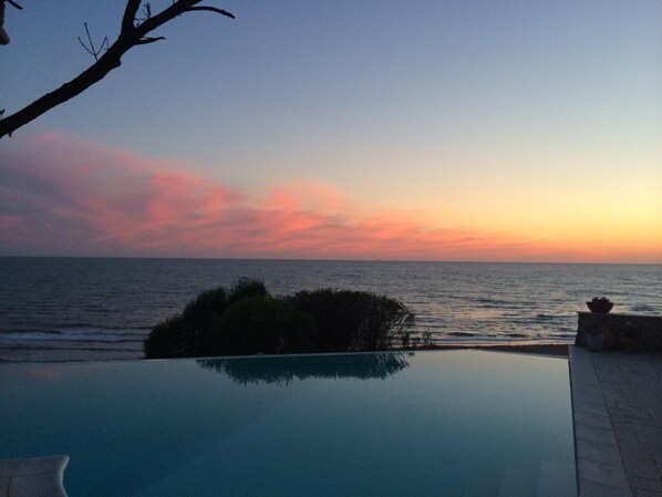 A pool with a view of the ocean at sunset. - Dream location- Modern villa with pool by the sea, just a stone's throw from Rome. (Anzio)