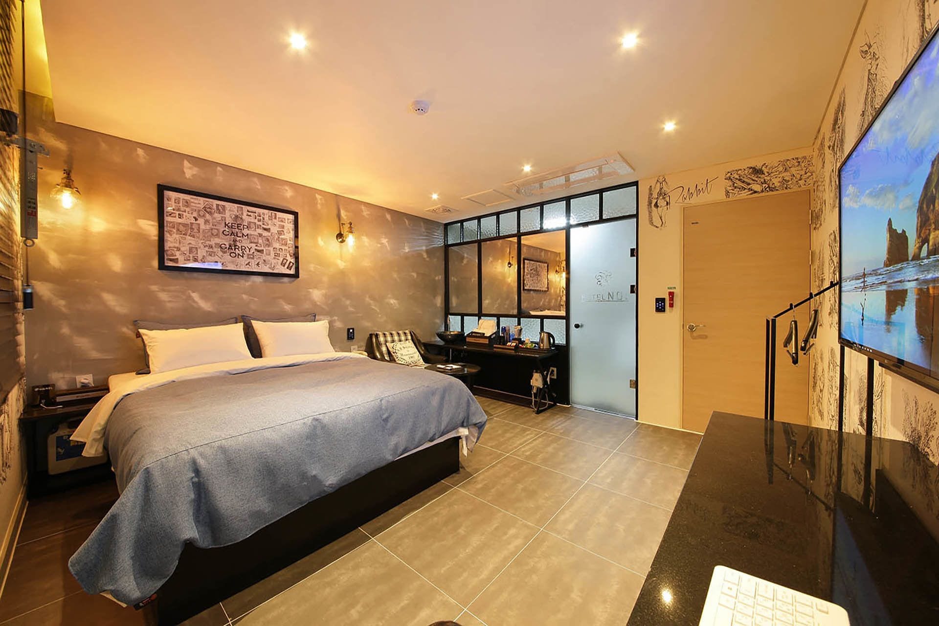 Una habitación de hotel moderna con una cama grande, un escritorio y una televisión.