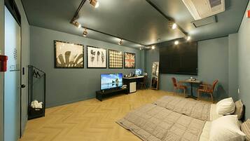 Ein Hotelzimmer mit Bett, Schreibtisch, Fernseher und Kunstwerken an den Wänden.