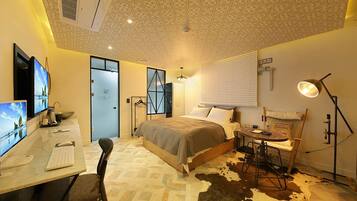 A hotel room with a bed, desk, computer, and a cowhide rug.