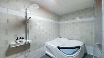 Un baño moderno con una bañera independiente, un cabezal de ducha y un estante con artículos de aseo.