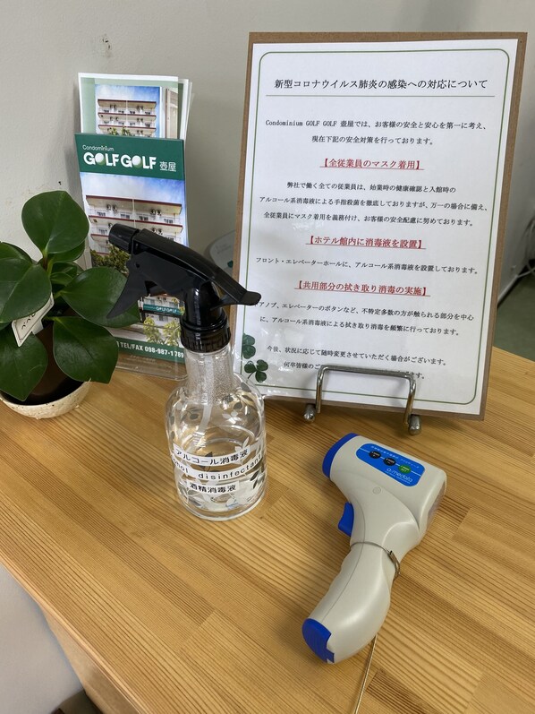 A bulletin board with safety information, a spray bottle labeled disinfectant, and a handheld sprayer on a wooden table.