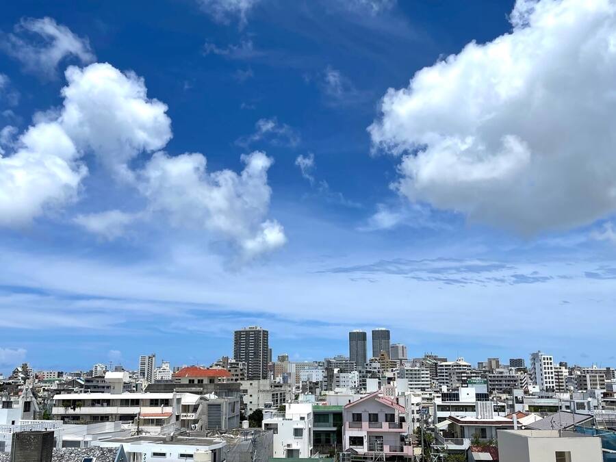 A cityscape with a variety of buildings, including residential and commercial structures, under a partly cloudy sky.