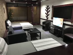 Un salon moderne comprenant un canapé, deux fauteuils, une table basse, un téléviseur et un petit balcon avec vue.