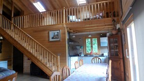 Eine Holzhütte mit Essbereich, Küche und einer Treppe, die zwei Ebenen verbindet.