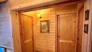 Ein hölzerner Flur mit zwei Türen, einem gerahmten Bild an der Wand und einer Leuchte darüber.