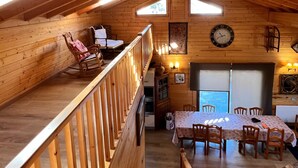 Ein Holzinnenraum mit Treppe, Essbereich und einer Uhr an der Wand.
