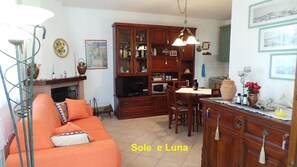Un salon chaleureux avec un canapé, une cheminée et un coin repas agrémenté de meubles de rangement en bois et d’un téléviseur.