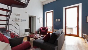 Un soggiorno moderno con una scala, un divano rosso, un divano grigio e una televisione.