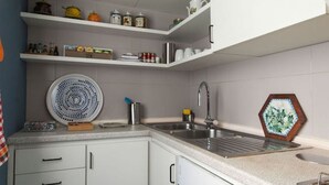 Una cucina moderna con mobili bianchi, un lavello in acciaio inossidabile e diversi oggetti da cucina sugli scaffali.