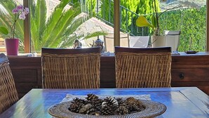 Un comedor con una mesa preparada para dos personas, con un centro de mesa tejido y vistas a las montañas a través de amplios ventanales.