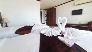 Habitación de hotel con dos camas, cada una decorada con almohadas en forma de cisne blanco y una manta marrón.