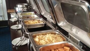 A buffet setup with multiple stainless steel chafing dishes containing various food items.