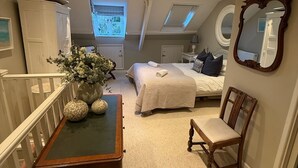 A bedroom with a bed, a chair, a table with vases, a mirror, and a wardrobe. - Beautiful Holiday Cottage next to beach in Cawsand, SE Cornwall - dog friendly! (Cawsand)