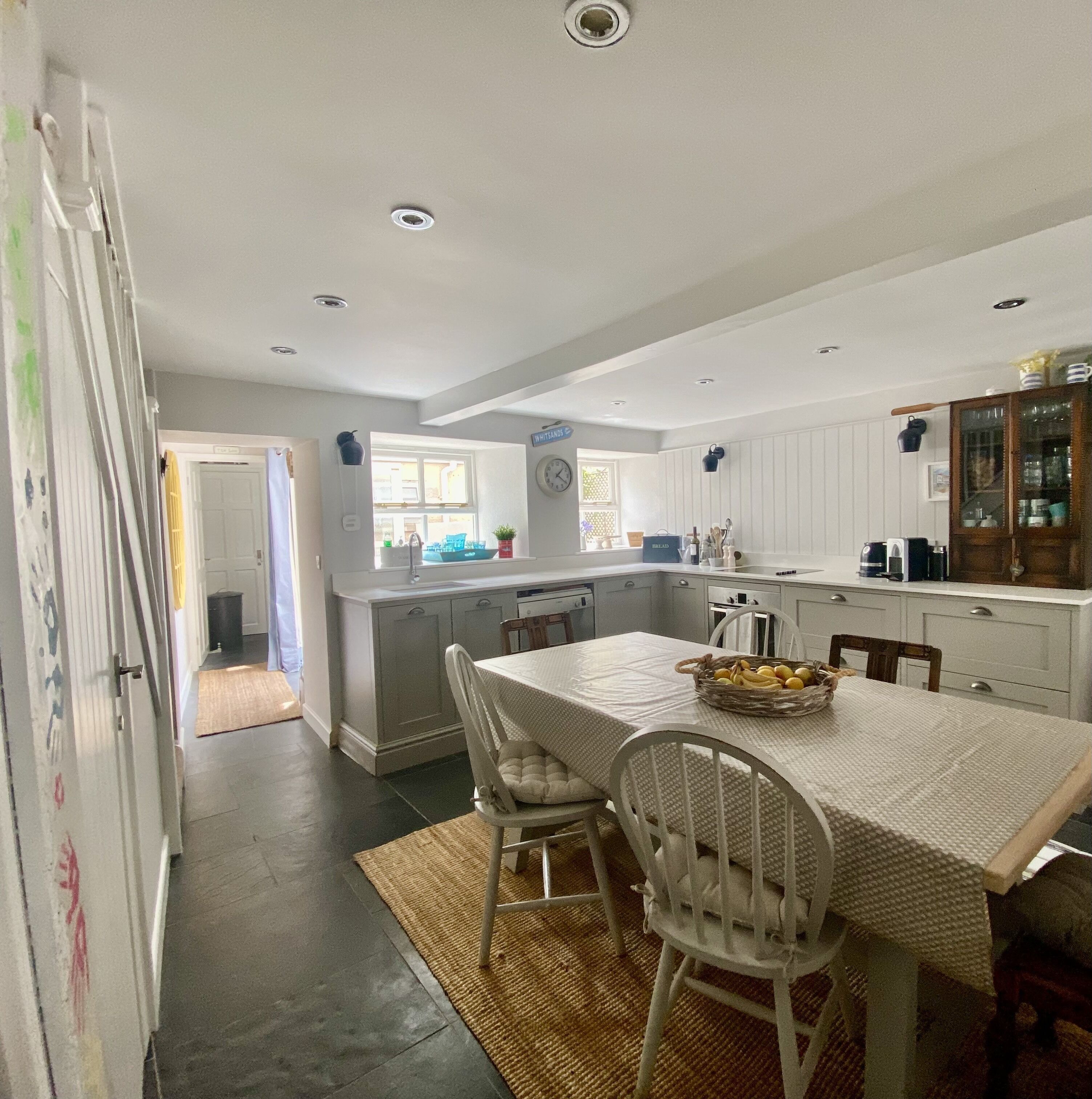 A kitchen with white cabinets, a dining table with chairs, and a window.