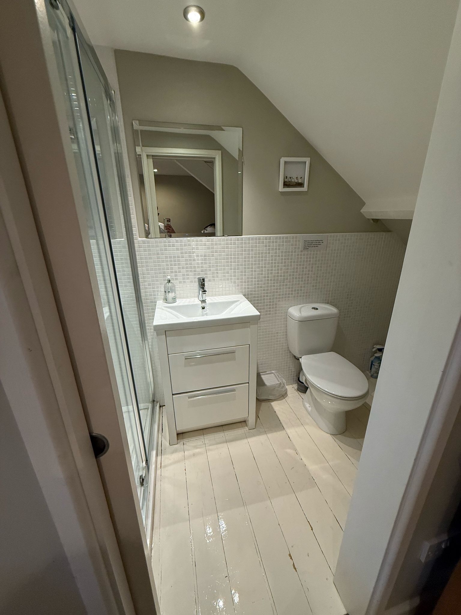 A bathroom with a white sink, mirror, and toilet.