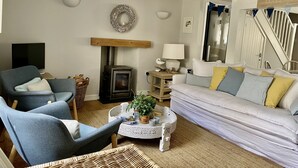 A cozy living room with a fireplace, a sofa, a chair, and a television. - Beautiful Holiday Cottage next to beach in Cawsand, SE Cornwall - dog friendly! (Cawsand)