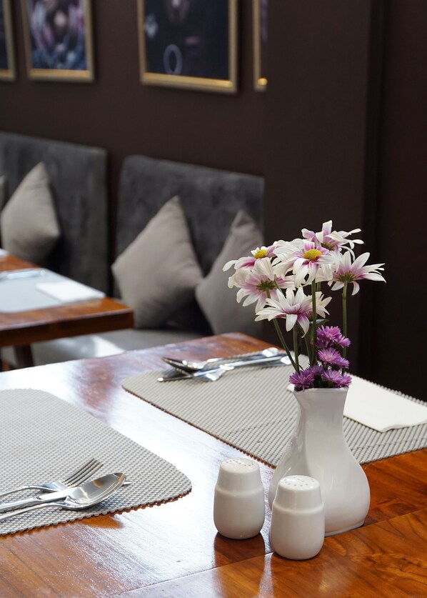 A dining table with a vase of flowers, salt and pepper shakers, and cutlery.