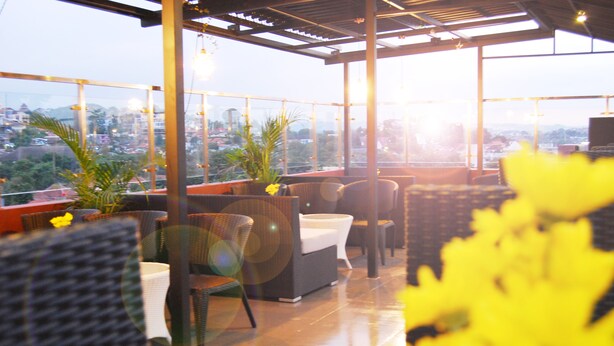 Terraza en la azotea con mobiliario de mimbre, plantas en macetas y vistas a la ciudad.