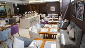 Un restaurante moderno con varias zonas de estar, incluidas sofás y mesas, y una zona de bar con mostrador y taburetes.