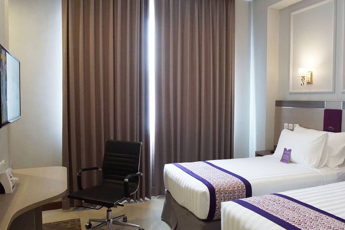 Una habitación de hotel con dos camas, un escritorio, una silla y un televisor.