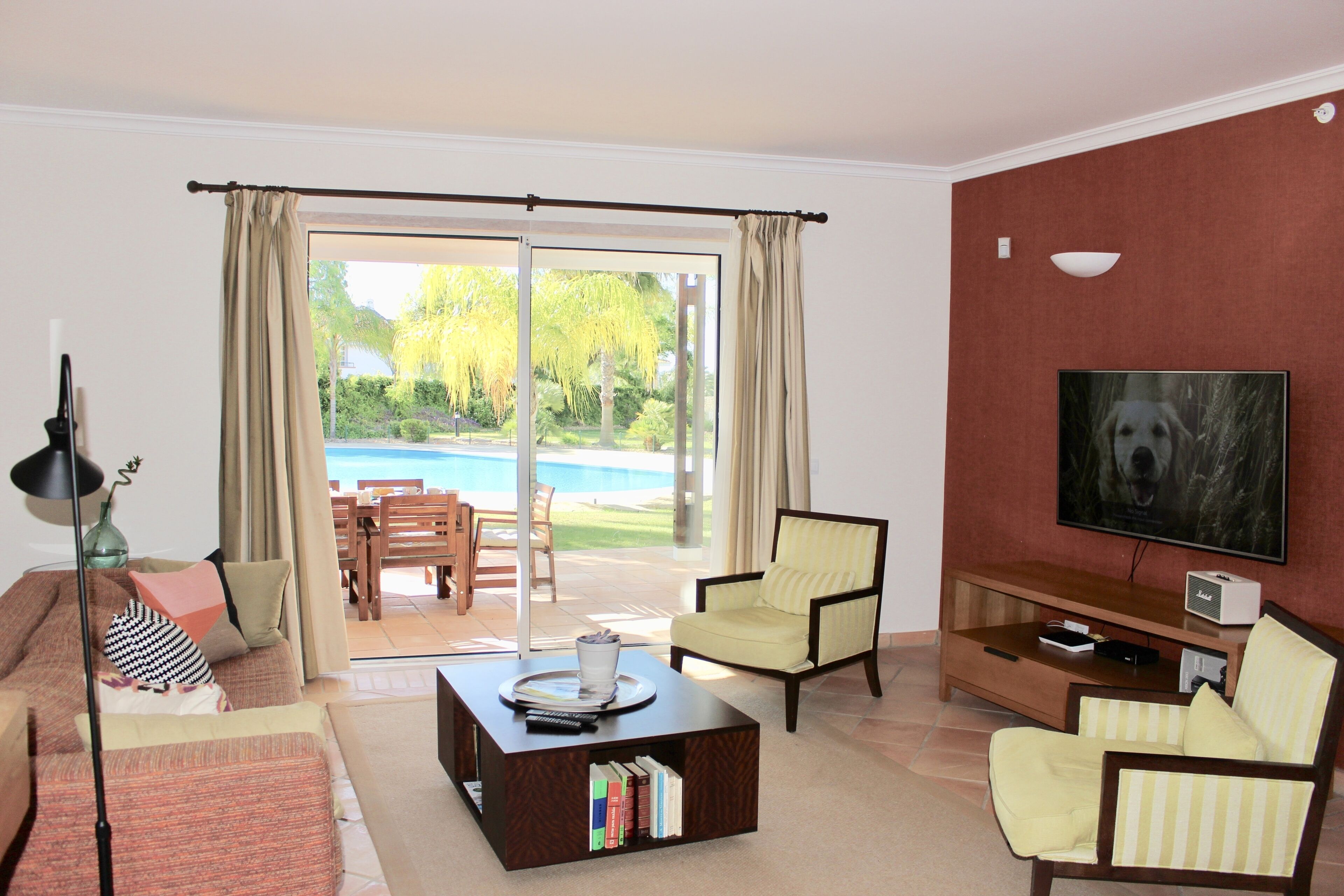 A living room with a pool view, a television, and a bookshelf.